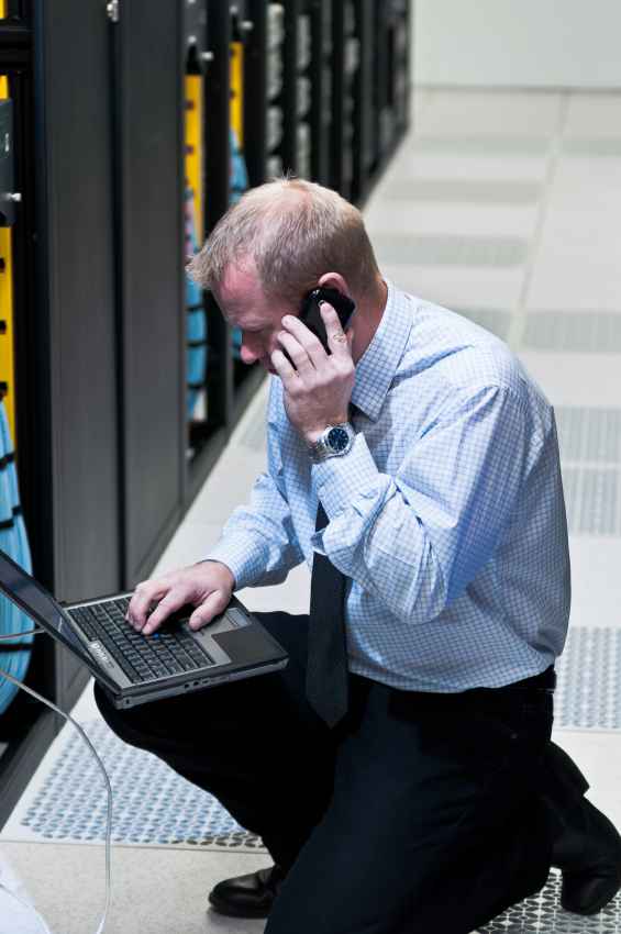 Man working in server room with a laptop